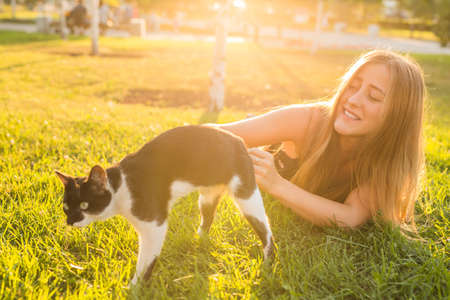 Pets and owner concept - Beautiful girl playing with a cat in the grass.の写真素材
