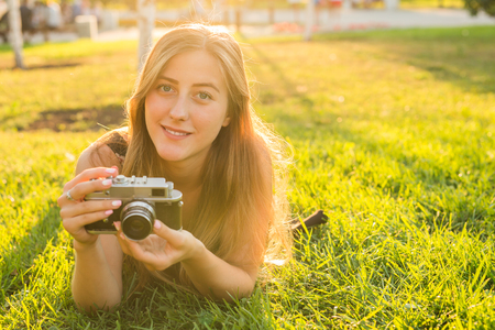 Pretty girl lying on the grass with vintage camera.の写真素材