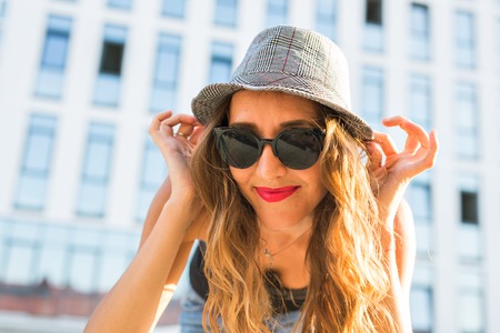 Summer sunny lifestyle fashion portrait of young stylish hipster woman walking on the street, wearing cute trendy outfit, smiling enjoy her weekendsの写真素材