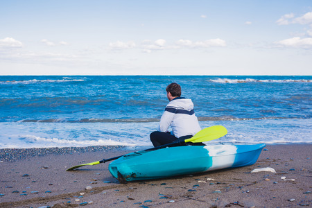 Man sitting on the beach with kayakの写真素材