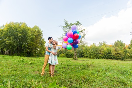 summer holidays, celebration and dating concept - couple with colorful balloons in natureの写真素材
