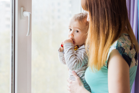 Loving mother playing with her baby son near a windowの写真素材