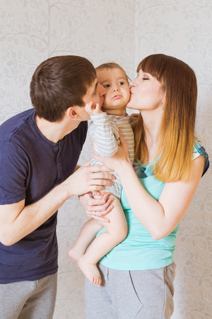 Young happy parents kissing baby boyの写真素材