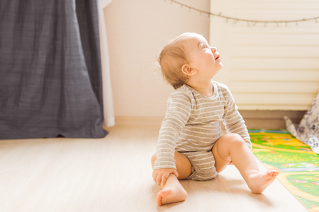 Cute baby boy toddler sitting on the floor in bedroomの写真素材