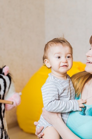 Portrait of happy adorable baby boy with mother indoorsの写真素材