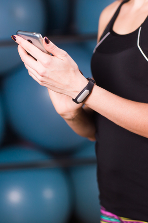 Close-up of female hands with fitness tracker and smartphone in gymの写真素材