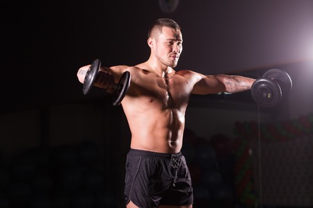 Portrait of strong healthy handsome Athletic Man Fitness Model posing with a dumbbell.の写真素材