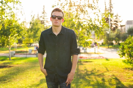 Handsome stylish hipster man in sunglasses posing at sunshine nature, enjoying beautiful viewの写真素材