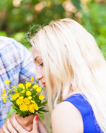 Young man giving a flower dandelion to girlfriend outdoorsの写真素材