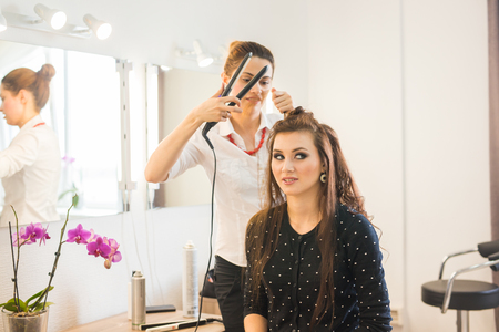 beauty and people concept - happy young woman with hairdresser at hair salon.の写真素材