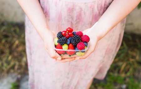 healthy eating, dieting, vegetarian food and people concept - close up of woman hands holding berries outdoorの写真素材