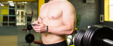 Workout smart fitness concept.Close-up of Young Muscular athlete checking training program on smartphone application after perfect crossfit in gymの写真素材