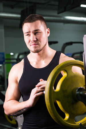 Young sportsman preparing his barbell by twisting power disk in.の写真素材