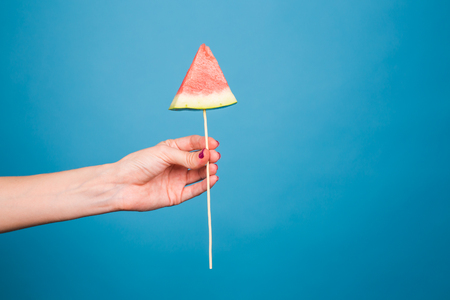 Summer, vacation, diet and vegans concept - Close-up of womans hand holding watermelon slice on stickの写真素材