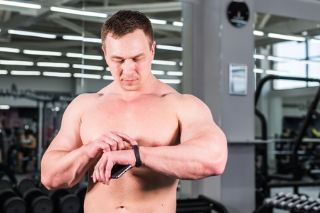 sport, fitness, technology and people concept - man with heart-rate watch and smartphone in gymの写真素材