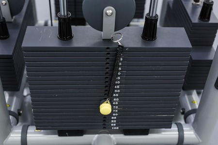 Black iron heavy plates stacked of weight machine in fitness gym. Sports simulator plates