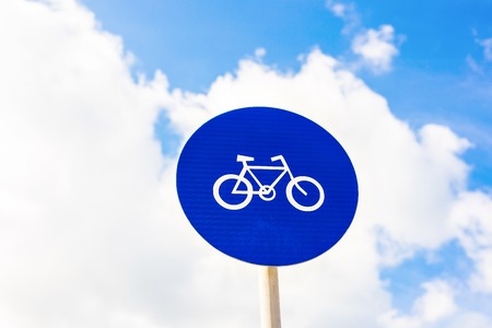 round bicycle lane sign against a blue sky.の写真素材