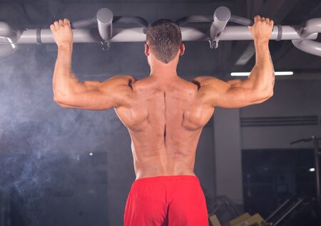 A young man doing pull ups in the Gym