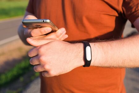 Sport, gadget, activity tracker and people concept - Close up of runner jogging outside looking at his wearable fitness bracelet.の写真素材