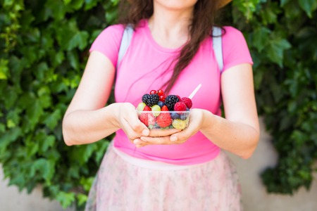 healthy eating, dieting, vegetarian food and people concept - close up of woman hands holding berries outdoorの写真素材