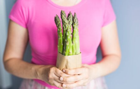 Female hand holds Bundle of green asparagus. Concept of vegans, vegetarians and healthy foodの写真素材