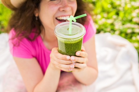 Close up of Young woman have fun in the park and drink green smoothies at a picnic.の写真素材