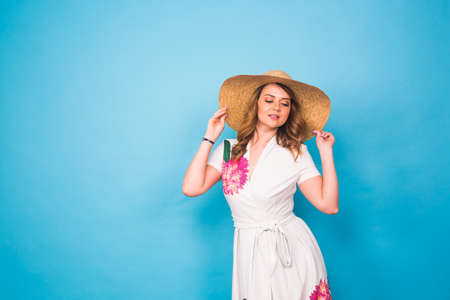 Holidays, summer, fashion and people concept - Girl in fashionable clothes straw hat. Portrait of charming woman on blue background with empty copy space.の写真素材