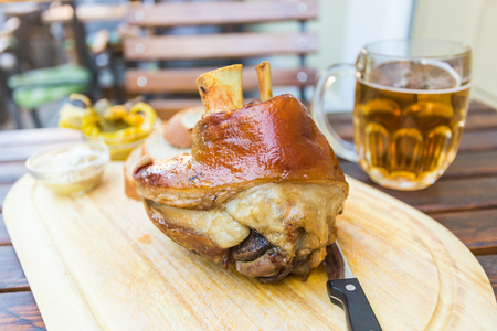 eisbein with bread, vegetables and beer on wooden cutting boardの写真素材