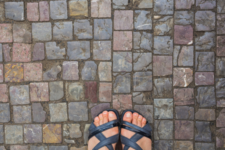 Feet selfie from upper view of a woman traveler in sandal during a tour trip around the world. Tourist take a photo of her own leg.の写真素材