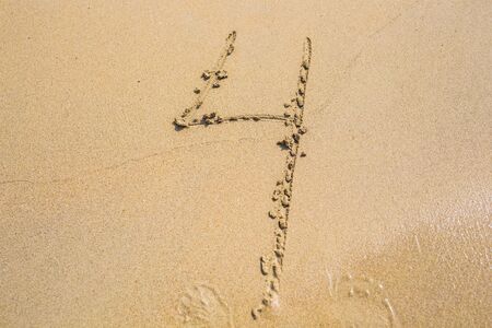 The number four drawn on sand at the beach, holiday concept background