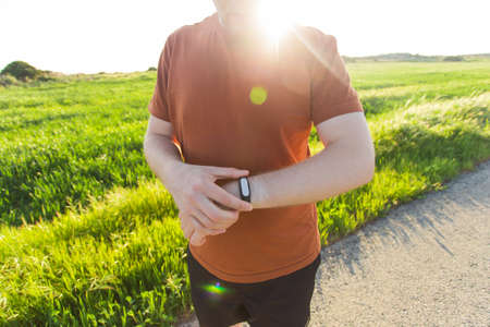 Close-up of Male runner jogging outside looking at his wearable fitness tracker outside.