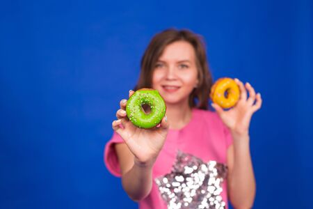 Young beautiful woman with doughnut on blue backgroundの写真素材