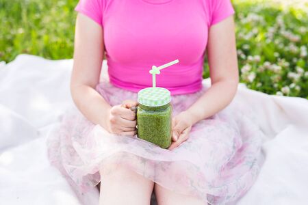 Close-up of Young woman holding green smoothies at a picnic. Healthy food, detox and diet conceptの写真素材