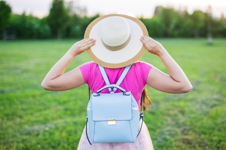 Young female with blue backpack and hat enjoying the countryside, back viewの写真素材
