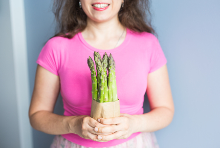 Female hand holds Bundle of green asparagus. Concept of vegans, vegetarians and healthy foodの写真素材