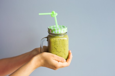Healthy green smoothie in womans hand. Vegan, raw food, detox and diet lifestyle.の写真素材