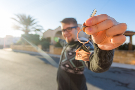 Property, ownership, new home and people concept. Cheerful young man holding house key.の写真素材