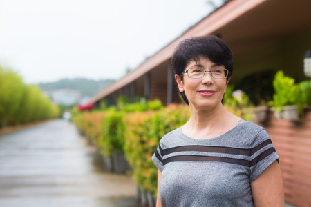 Close-up portrait of beautiful woman standing on the street while looking at camera and smilingの写真素材