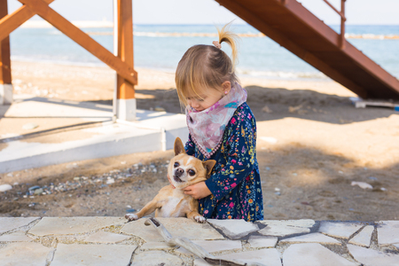 Happy little baby girl playing with dog outdoorの写真素材