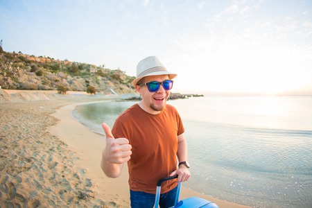 Handsome happy man giving thumbs up on the beach.