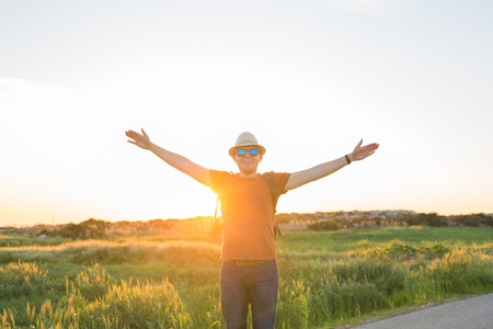 young man at sunset raises his hands upの写真素材