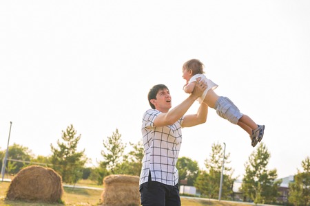 Father and son playing on the field at the day time. People having fun outdoors. Concept of friendly familyの写真素材