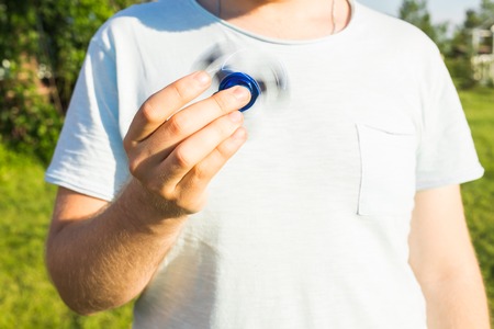 Close up of man playing with a blue hand spinner fidget toyの写真素材