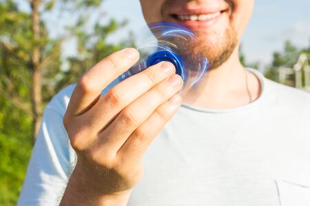 Close up of man playing with a blue hand spinner fidget toyの写真素材