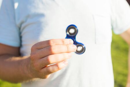 Close up of man playing with a blue hand spinner fidget toyの写真素材