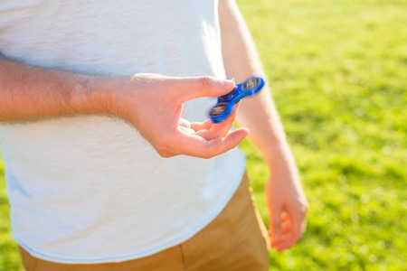 Close up of man playing with a blue hand spinner fidget toyの写真素材