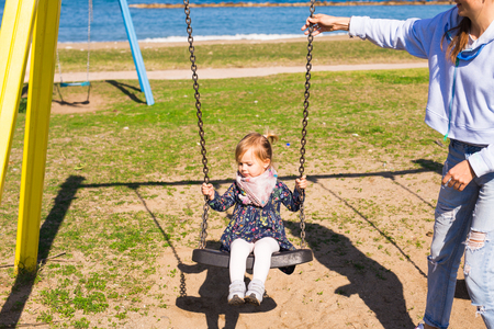 Happy child girl on swing in summer dayの写真素材