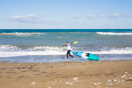 Man walking on the beach with kayak. Traveling by sea. Leisure activities on the water.の写真素材