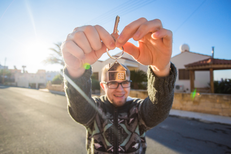 Young smiling man showing keys to new home. Real estate, apartment and people conceptの写真素材