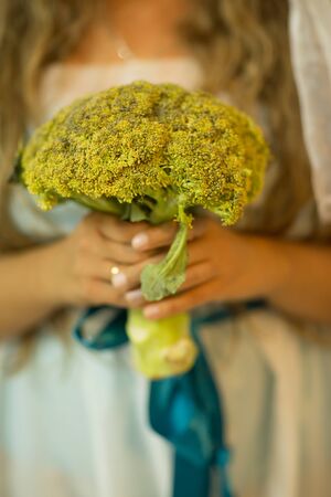 Fresh green broccoli in hands of a young womenの写真素材